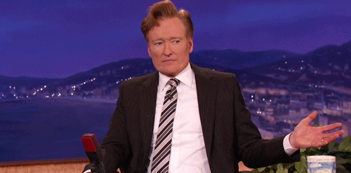 Late Night gif. Conan sits at his desk and looks around with his hand out, confused and looking for an answer from the audience.