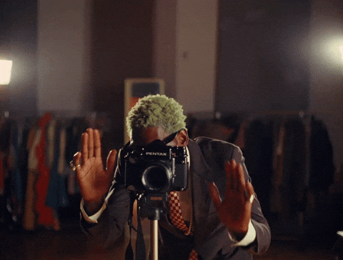 A man is standing behind the camera, searching for the perfect angle.