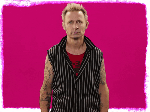 Celebrity gif. Mike Dirnt of Green Day slams a fist into his forehead with a look of annoyance. 