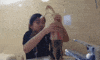 Video gif. An uncomfortable young girl tries to hold onto an overflowing bottle of Diet Coke.