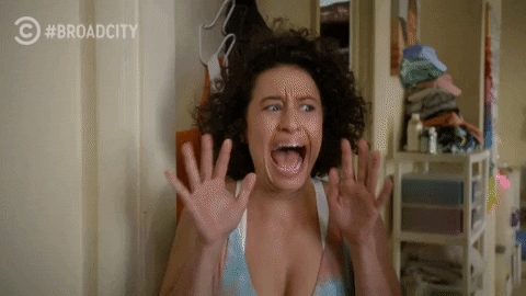 TV gif. Ilana Glazer as Ilana on Broad City screaming, terrified, with her hands up to her face, before she slowly calms down.