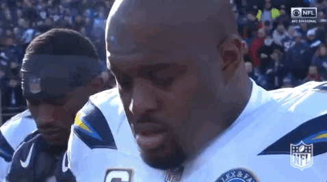Sports gif. Standing on the field during a game, Brandon Mebane of the Los Angeles Chargers blows a kiss to the sky and exhales, his breath showing in the frigid air.