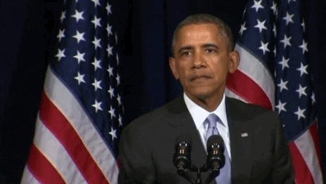 Political gif. Obama is standing at a podium and the American flag is behind him. He listens attentively before showing a confused face, scrunching his brows and narrowing his eyes. He lifts a his hand up as if disbelieving what he's heard.