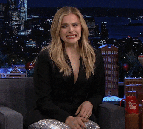 Celebrity gif. A guest on The Tonight Show, Chloë Grace Moretz laughs and shakes her head in disbelief, then covers her face with her hand.