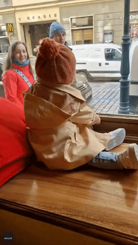 Baby Sitting in Shop Window Delights Passersby in Prague