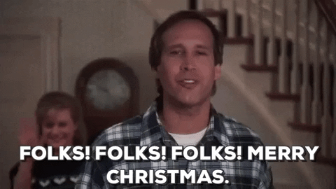 Movie gif. Chevy Chase as Clark in National Lampoon’s Christmas Vacation looks upon his family and friends with a proud grin and says, “Folks! Folks! Merry Christmas.” Beverly D’Angelo as Ellen Griswold stands behind him waving, opening and closing her hand, and smiles so wide that she crinkles her nose.