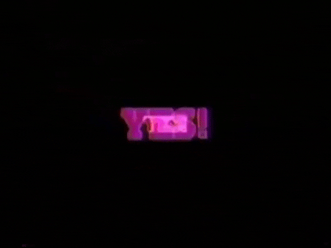 Text gif. Pink glowing text zooms in from a black background, reading "yes!"