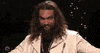 SNL gif. Jason Momoa smiles devilishly while looking around and holding out his arms.