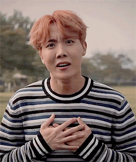 Celebrity gif. K-pop star J-Hope holds his hands to his chest in sincere gratitude and smiles.