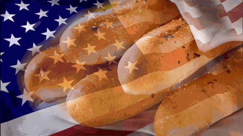 Video gif. Stack of breadsticks appears through an American flag overlay that ripples across the screen.