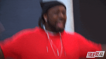 Reality TV gif. A Rapper on The Rap Game jumps around excitedly, waving his hands in the air. He smiles widely and looks around with wide eyes.