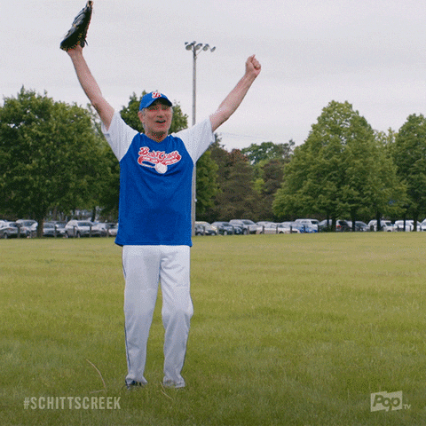 Schitt's Creek gif. Eugene Levy as Johnny wears a baseball uniform as he cheers with his arms up before pointing and saying, "That's my boy!"