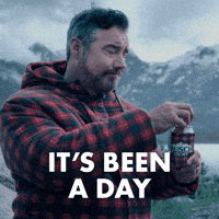 Sponsored gif. Burly man in a red and black plaid sweatshirt cracks open a can of Busch Light beer in a matching koozie. Text reads, “It’s been a day.”