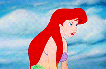 Disney gif. Ariel in The Little Mermaid looks down in concern as a glowing light rises up, then she looks up with surprise and elation.