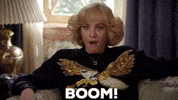 TV gif. Wendi McLendon-Covey as Beverly in The Goldbergs. She's lounging on a couch listening to good news and she yells, "BOOM," while clenching her fists and smiling, wide-mouthed.