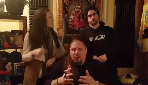 Video gif. Brimstone, Kimberly Adragna, and Steve Zambito of The Grindhouse Radio point in conflicting directions.