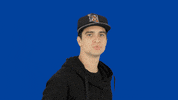 Celebrity gif. Brendon Urie stands in front of a solid blue backdrop and flicks his head back sassily while chewing his gum with attitude. He confidently walks away while staring straight at us.