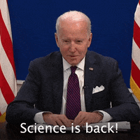 Political gif. President Joe Biden sits in between two American flags and grins happily while saying, "Science is back!"