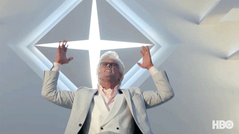 TV gif. Walton Goggins as Baby Billy Freeman from The Righteous Gemstones seems to be having a spiritual moment. Wearing white clothes in a white room, he raises his hands emphatically beneath a four-pointed star decoration.