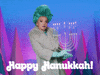 Video gif. Woman wearing a turquoise-colored wig in an elegant updo, tan fur coat, and teal gloves delicately holds up a Hanukkah menorah, striking a seductive pose. Text, "Happy Hanukkah."