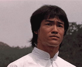 Celebrity gif. Bruce Lee trembling with fear and beginning to scream
