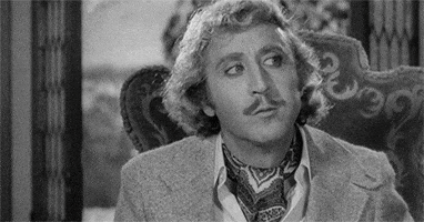 Movie gif. Gene Wilder in Young Frankenstein sits and faces us, looking around with his eyes as he thinks, raising his eyebrows slightly and tilting his head as he begins chewing again. 