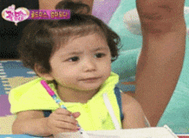 Video gif. A young toddler on a Korean show has a frustrated look on her face. She holds a marker with one hand and holds her other hand up. She yells, “Stop, stop!”