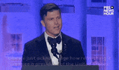 Video gif. Saturday Night Live's Colin Jost stands at a podium at the 2024 White House Correspondents' Dinner as he says, "Can we just acknowledge how refreshing it is to see a President of the United States at an event that doesn't begin with a bailiff saying all rise?"