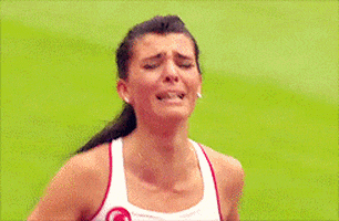 Sports gif. Looking exhausted, a sad track runner breaks down crying, then falls to her knees.