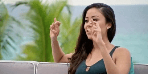 Reality TV gif. A contestant on Coupled is being interviewed and she puts both her hands in the air, showing double crossed fingers for luck.