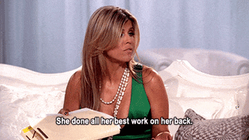 Reality TV gif. Wearing a green dress and several long necklaces, Ana Quincoces of Real Housewives of Miami holds a folder in one hand while casually throwing some serious shade. Text, "She done all her best work on her back."
