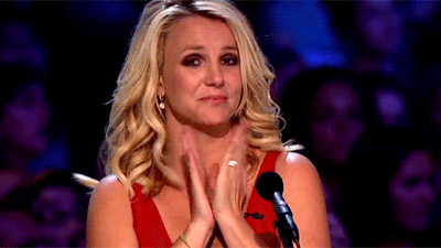 TV gif. Britney Spears on The X Factor claps, touched and almost teary eyed, from her judge's seat.