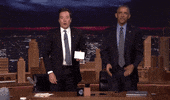 TV gif. Standing behind the desk of The Tonight Show next to Jimmy Fallon, Barack Obama claps and waves to us and says, “Thank you.”