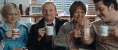 Movie gif. Simon Pegg as Shaun in Shaun of the Dead sips raises a triumphant cup of tea and winks at us.