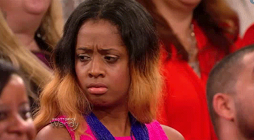 TV gif. A young woman sits among laughing women in the audience of the Wendy Williams Show and glances around confused. 