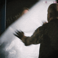 Sponsored gif. Man rips down a drop cloth and reveals the haunted doll Megan in her cardboard box. Text reads, “Surprise.”