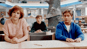 Movie gif. Sitting at tables in the library, Molly Ringwald as Claire, Emilio Esteves as Andrew, and Anthony Michael Hall as Brian in The Breakfast Club simultaneously shrug their shoulders.