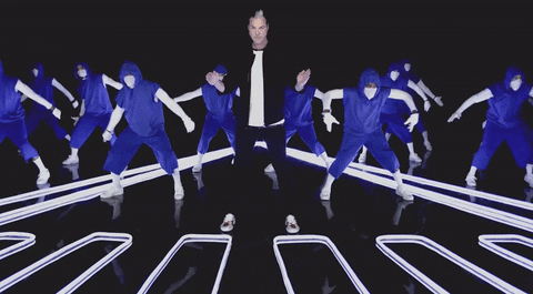 Music video gif. Fitz and The Tantrums are clapping in sync during a music video. The backup dancers are dressed in blue hoodies and sweatpants.
