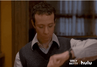 TV gif. Kevin Sussman as Walter in Ugly Betty holds up his wrist as he looks down at his watch impatiently.