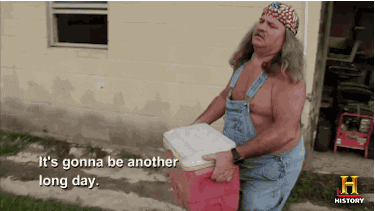 TV gif. An older man from Swamp People with long gray hair, wearing shirtless overalls and an American flag bandanna carries a red cooler out of a house. He speaks to us with a vague frown. Text, "It's gonna be another long day."
