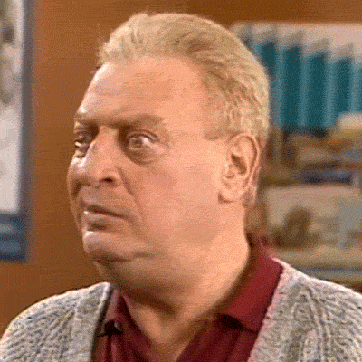 Celebrity gif. Rodney Dangerfield's eyes are wide and his mouth twitches left and right, as if he is malfunctioning and confused.