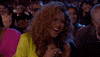 Celebrity gif. Beyonce's face lights up with laughter as she claps happily for someone at the BET Awards. She looks radiant with a neon yellow dress and curls that hang loosely over her face. Behind her, the rest of the crowd is also smiling and applauding.