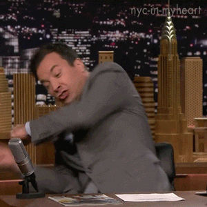 The Tonight Show gif. Jimmy Fallon sits at his desk and throws his body around in his chair like he’s wrestling the air. 