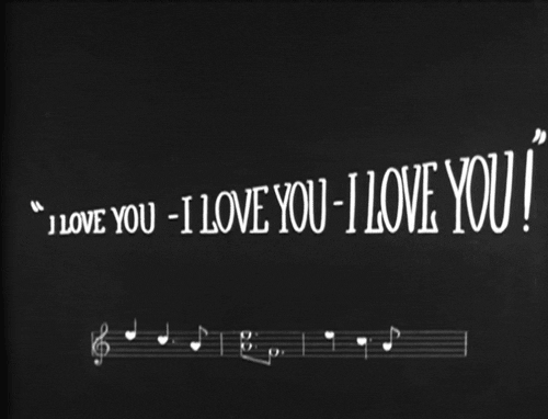 Text gif. Intertitle from a 1920s movie with quoted text that reads "I love you, I love you, I love you!" above a measure of musical notes.