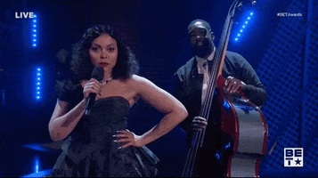 Celebrity gif. Taraji P Henson at the 2022 BET Awards looks at us with a microphone and with her other hand on her hips, then suddenly looks to the left and says, "Oh?"