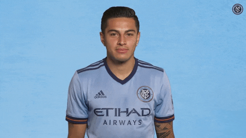 Sports gif. Ronald Matarrita from NYCFC is wearing his soccer jersey and he smiles softly as he shrugs his shoulders nonchalantly.