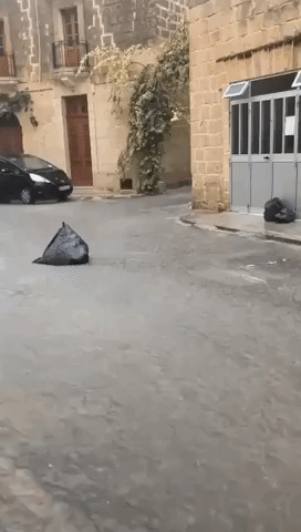 Trash Bags Float Down Street as Flooding Hits Malta