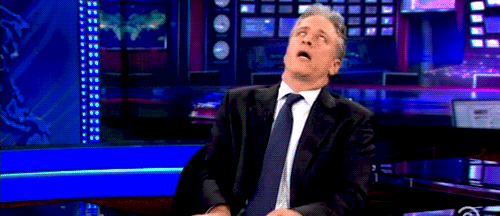 Celebrity gif. Exasperated Jon Stewart is on the set of The Daily Show, dramatically leaning so far back in his chair that he almost falls off.