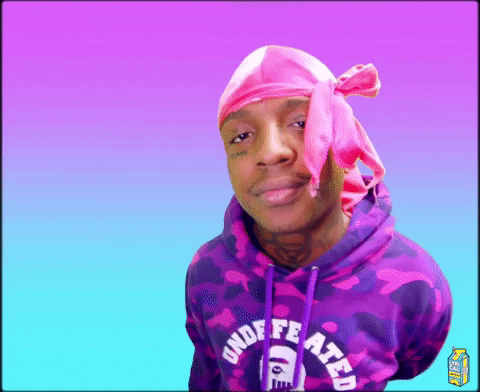 Video gif. Man in a hot pink durag and purple camo hoodie looks up at us with a smile and waves.