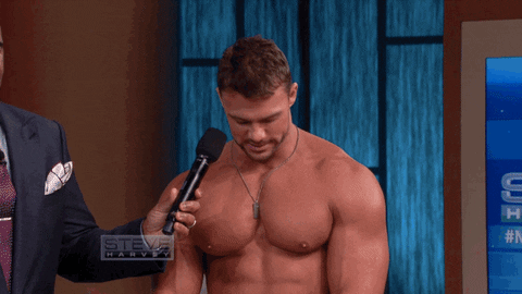 TV gif. Man with enormous pecs is on Steve Harvey TV and he bounces his pecs for the camera while the hosts giggle.